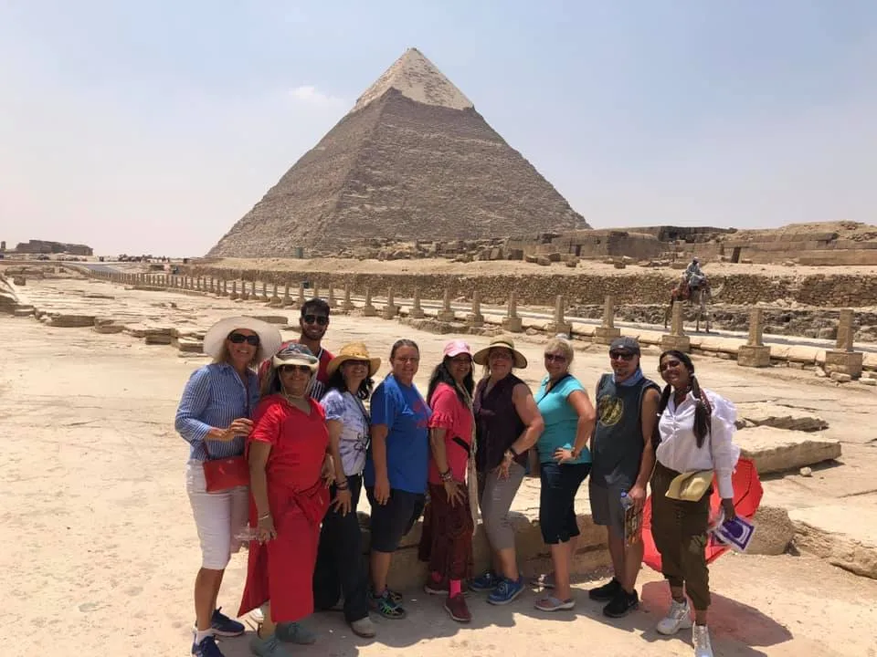Smiling individuals posing in front of the Pyramid of Egypt