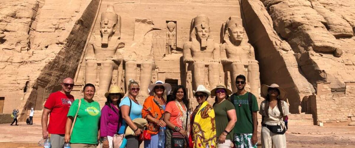 A tour group posed in front of the colossal statues at Abu Simbel, Egypt
